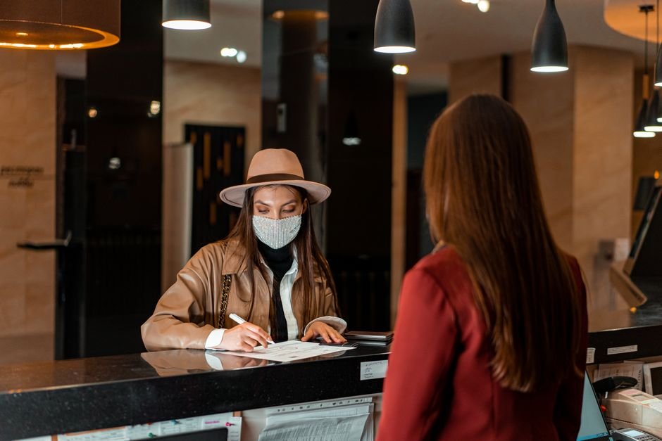 Recepcionista atenciosa ouvindo hóspede no balcão de atendimento