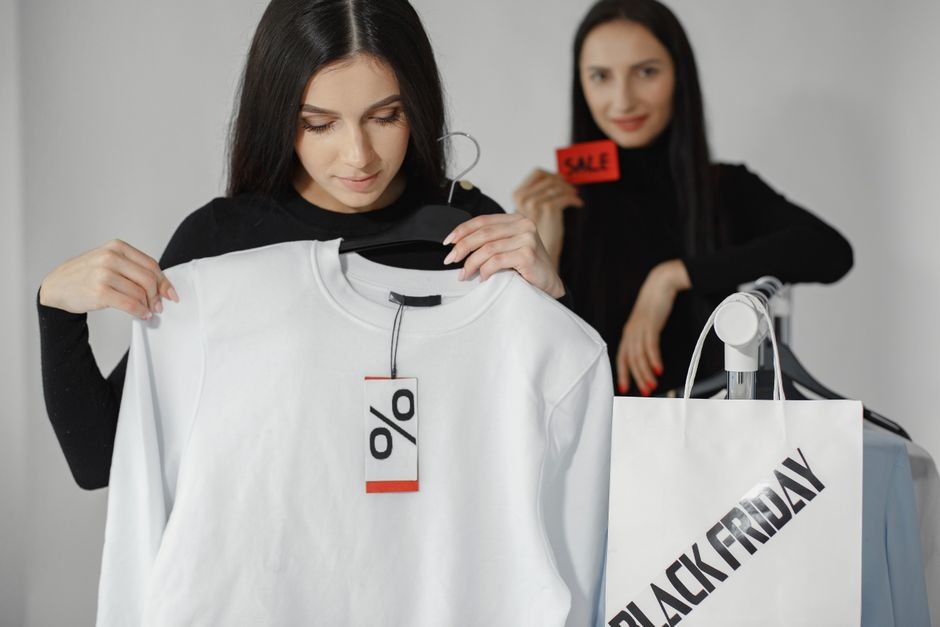 Arara de roupas em promoção com placa de desconto na loja